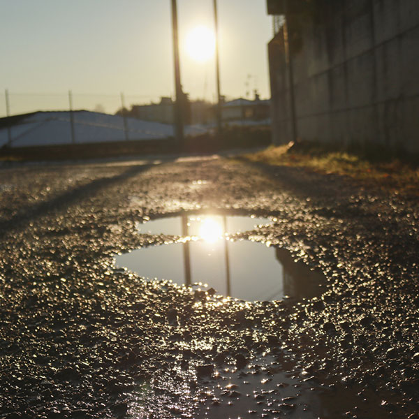 Pool of water in a country road with light reflected by the setting sun