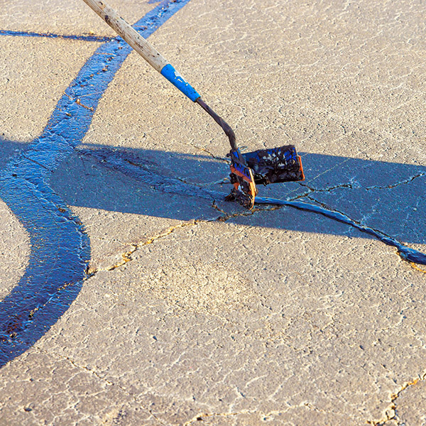 Course of worker patching are filled, asphalt cracks are sealed, bitumen emulsion is applied to restore road surface.