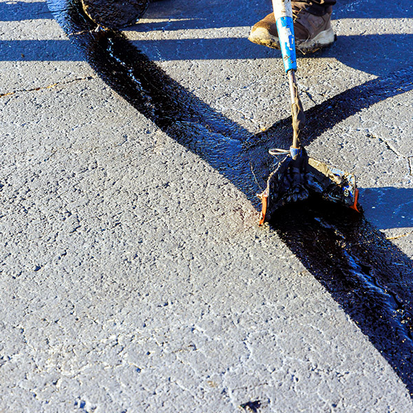 During worker patcher performs coated filling asphalt cracks sealing bitumen emulsion road surface restoration work